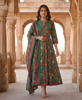 Woman in a green floral dress standing in an architectural setting with intricate carvings.